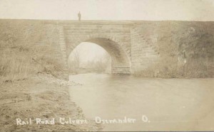 Vintage train trestle over creek, a figure of a man appears on the trestle