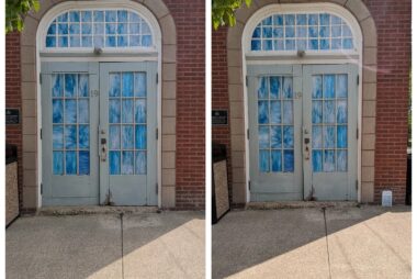 An old-fashioned, white door in Ostrander village with blue designs on its windows. There is a transom window above also covered with blue designs. To the right is a miniature version of this door created by Amy Margraff