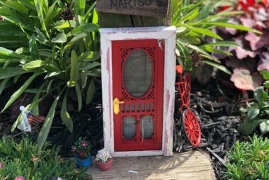 A small, red, old-fashioned miniature door