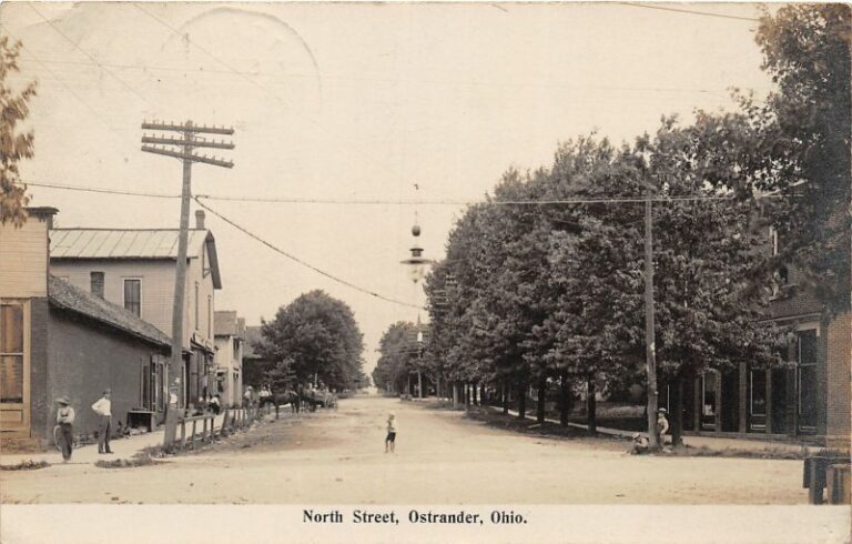 A few of North Street in Ostrander, Ohio A dirt road lined by trees on the right side, and old buildings and residents on the left side