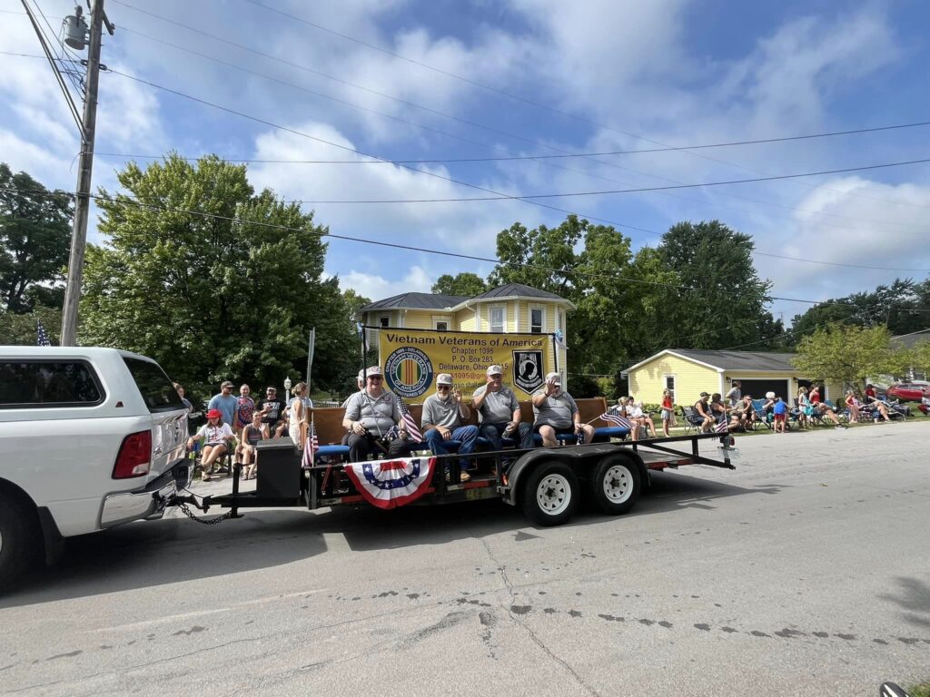 Vietnam veterans riding on a float pulled by a white truck in the 4th of July parade