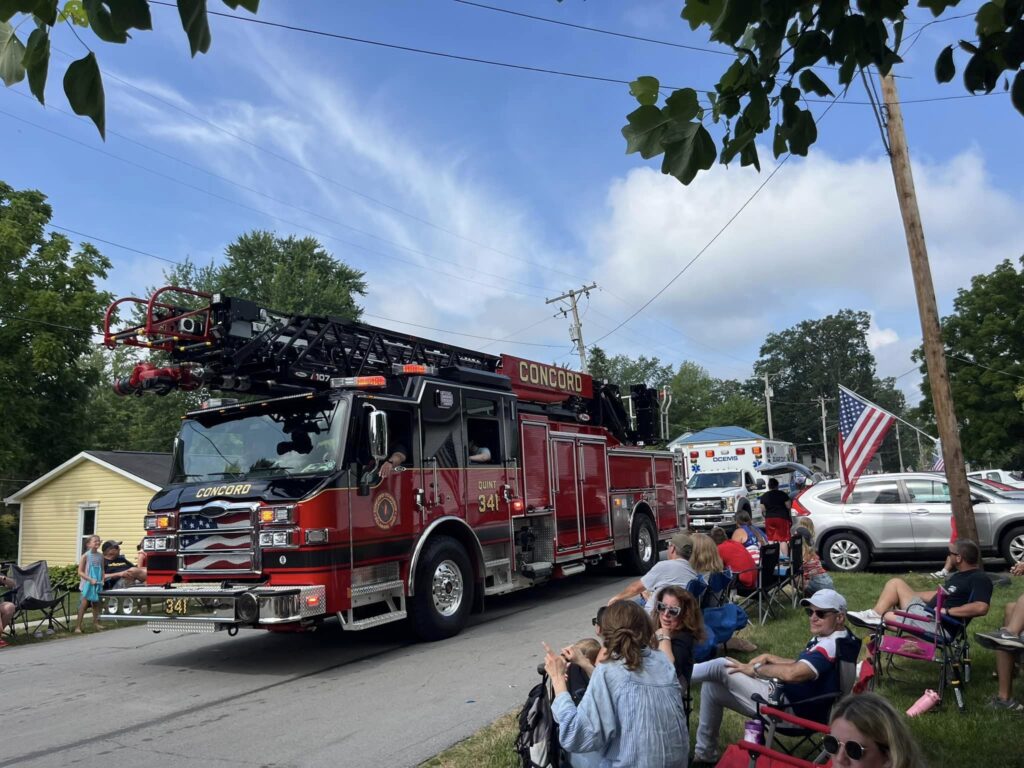 A large, red fire engine that says Concorde, participating in the 4th of July parade